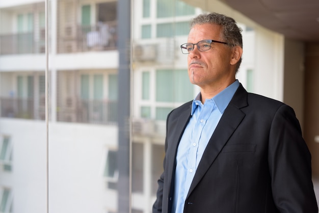 Portret van volwassen knappe zakenman bij het glazen raam