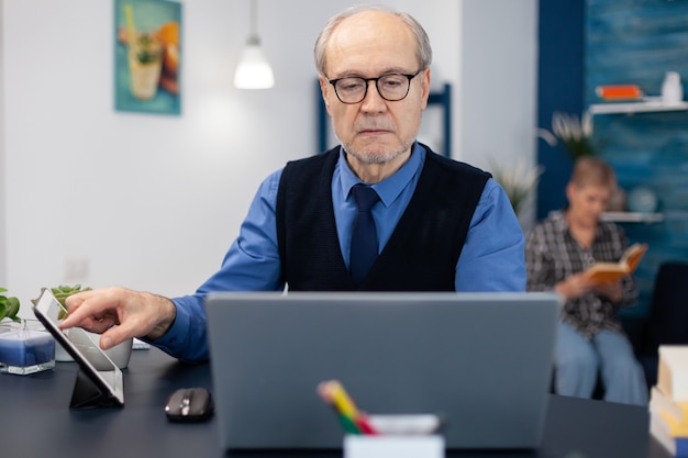 Portret van volwassen man die websurft op laptop vanuit kantoor aan huis