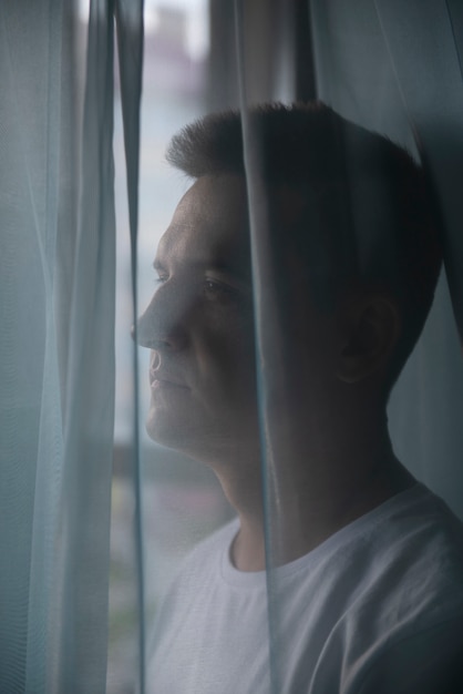 Foto portret van volwassen man met gordijnen en schaduw van raam