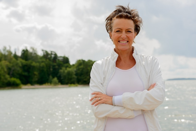 Portret van volwassen mooie vrouw tegen schilderachtig uitzicht op het meer en de lucht in de natuur