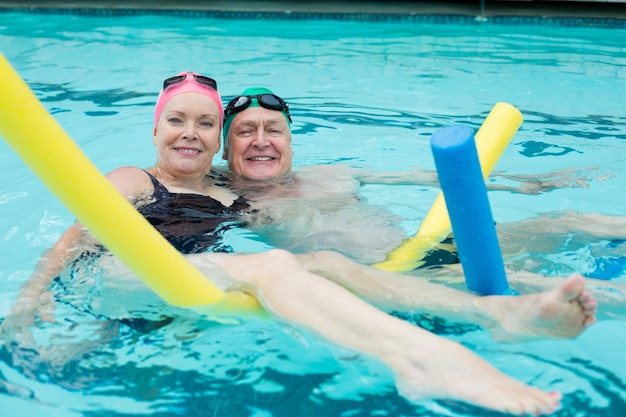 Portret van volwassen paar dat met poolnoedels zwemt