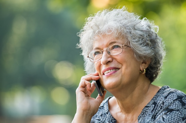 Portret van volwassen vrouw praten over smartphone buiten