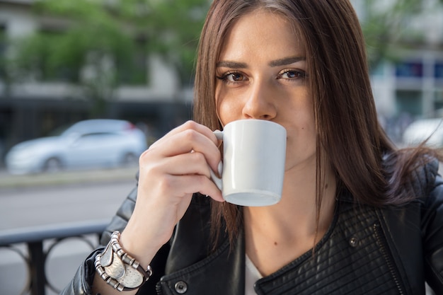 Portret van vrij kaukasische vrouw het drinken koffie op een terras in de straat.