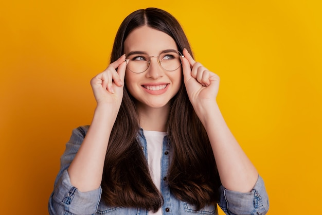 Portret van vrolijk lachend modemeisje past brillen op gele achtergrond aan