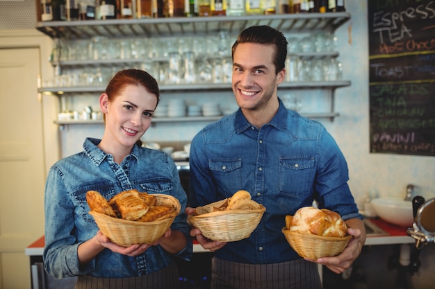 Portret van vrolijke barista's die broden aanbieden bij koffiewinkel