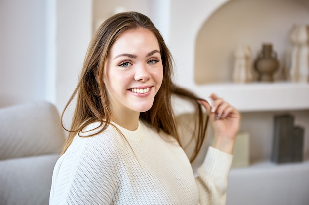 Portret van vrolijke blanke vrouw op de bank binnenshuis