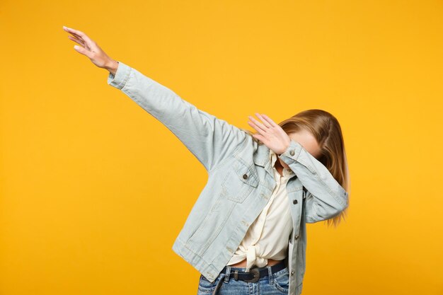 Portret van vrolijke blonde jonge vrouw in denim casual kleding met schar dans gebaar geïsoleerd op fel geel oranje muur achtergrond in studio. Mensen levensstijl concept. Bespotten kopie ruimte.