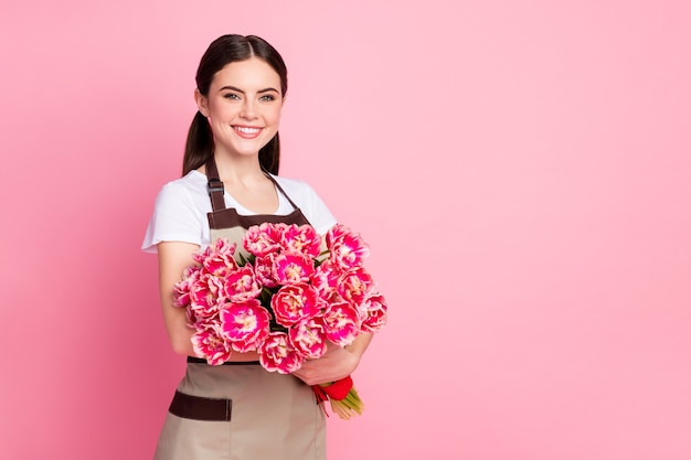 Portret van vrolijke content girl manager die romantische bloemen in handen houdt