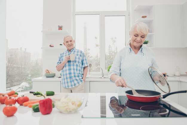 Portret van vrolijke geconcentreerde echtgenoten koken