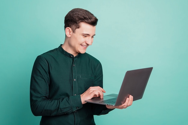 Portret van vrolijke gelukkige werknemer man houdt netbook glanzende witte glimlach op turkooizen achtergrond