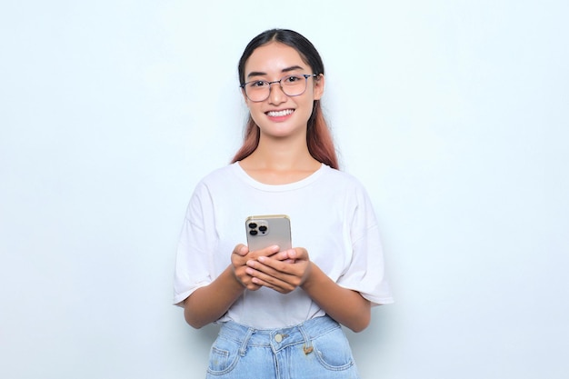 Portret van vrolijke jonge Aziatische meisje in witte t-shirt met behulp van mobiele telefoon geïsoleerd op een witte achtergrond