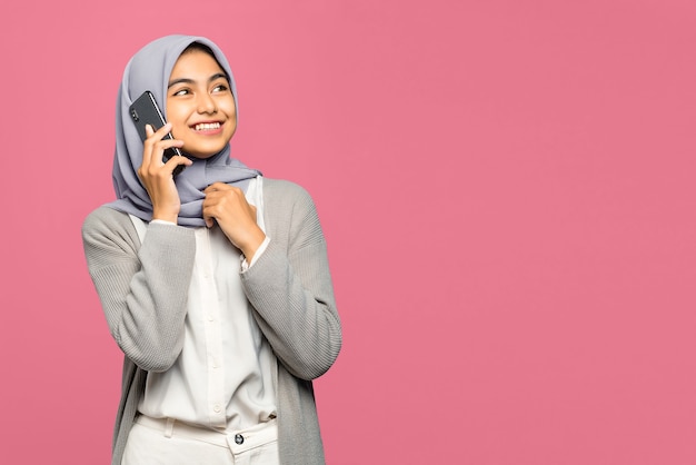 Portret van vrolijke jonge Aziatische vrouw die met vrienden in mobiele telefoon spreekt