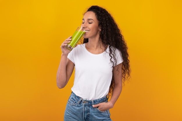 Portret van vrolijke jonge dame die smoothie drinkt