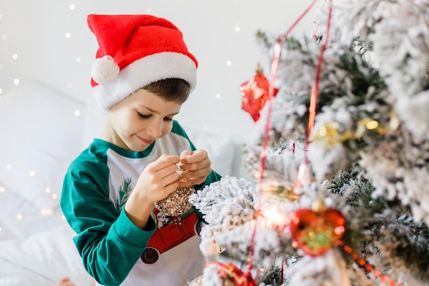 Foto portret van vrolijke jongen die glimlacht en lacht naast de kerstboom bij huis gezinnen en kinderen