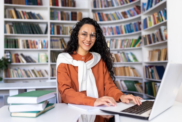 Portret van vrolijke lachende studente vrouw kijken camera zitten studeren met laptop