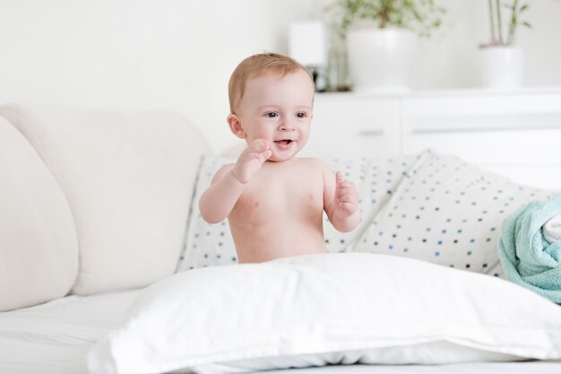 Portret van vrolijke naakte babyjongen spelen op bed met kussens
