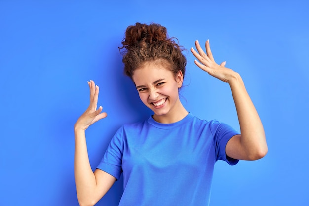 Portret van vrolijke vrolijk meisje poseren in studio, knappe vrouw in vrijetijdskleding is model, ze is in een goed humeur, glimlach