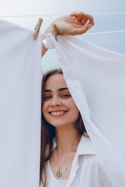 Foto portret van vrolijke vrouw in de buurt van witte lakens kijkend naar camera in de natuur