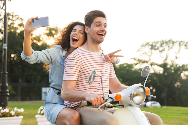 Portret van vrolijke vrouw selfie te nemen op smartphone, tijdens het rijden op de motor door stad straat samen met haar vriendje