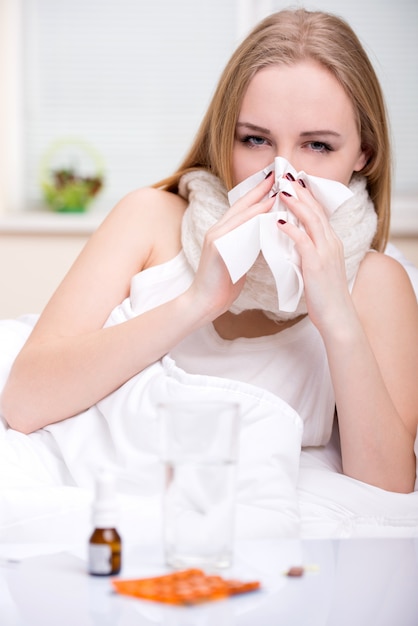 Portret van vrouw die aan koude in bed lijdt.