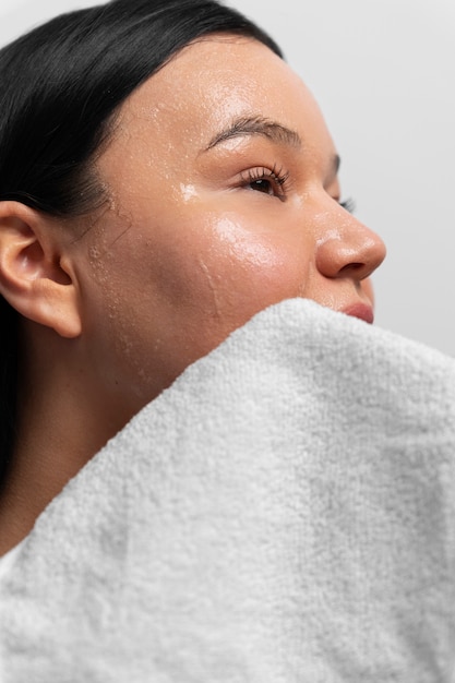 Foto portret van vrouw exfoliërend gezicht met product en handdoek