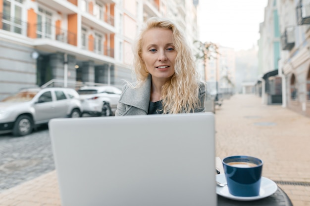 Portret van vrouw in warm in een openluchtkoffie met laptop