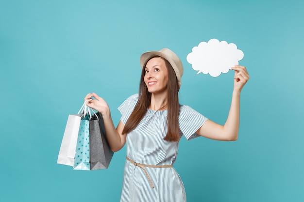 Portret van vrouw in zomerjurk, strohoed met pakketten met tassen met aankopen na het winkelen, lege blanco Say cloud, tekstballonkaart geïsoleerd op blauwe pastelachtergrond. Ruimte advertentie kopiëren