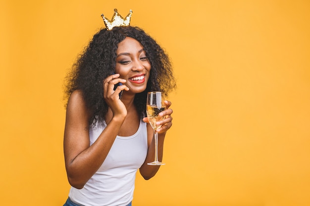 Portret van vrouw met glas champagne en gouden kroon die over de telefoon spreken