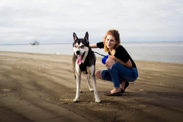 Portret van vrouw met hond op het strand tegen de lucht