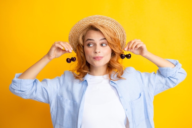 Portret van vrouw met kersen op gele studio geïsoleerde background