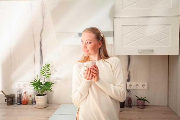 Portret van vrouw met kop in gezellige keuken