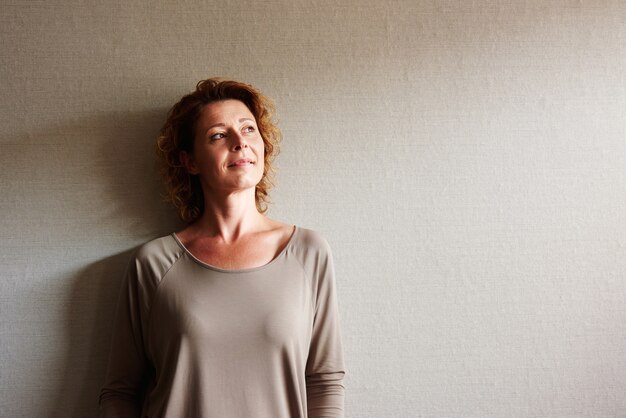 Portret van vrouw met krullend haar die op muur in overpeinzing leunen