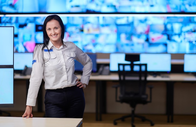 Foto portret van vrouwelijke beveiligingsoperator tijdens het werken in een datasysteem controlekamer kantoren technische operator werken op werkstation met meerdere beeldschermen, bewaker werkt op meerdere monitoren