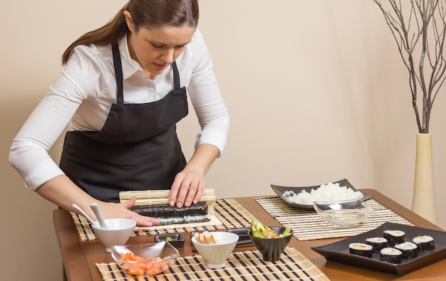 Portret van vrouwelijke chef-kok die een Japanse sushi oprolt