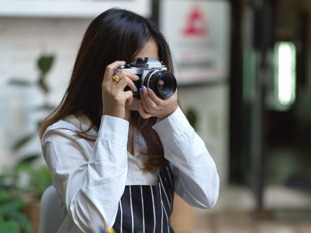 Portret van vrouwelijke fotograaf die foto met digitale camera in koffie neemt