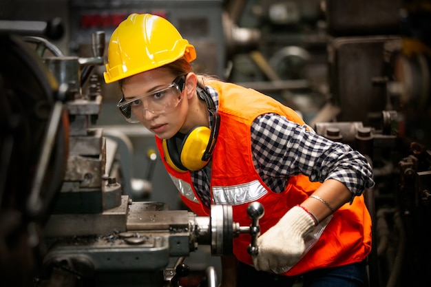 Portret van vrouwelijke ingenieur permanent met vertrouwen tegen machine-omgeving in fabriek