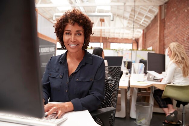 Portret van vrouwelijke klantenservicemedewerker die aan de balie in het callcenter werkt