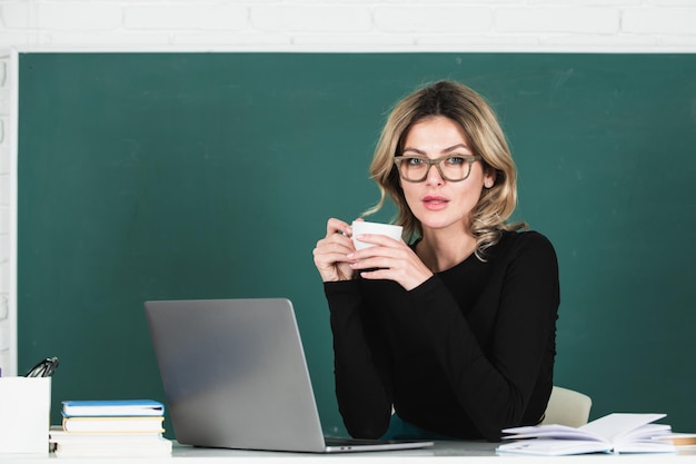 Portret van vrouwelijke leraar die koffie drinkt in de klas op blackboard