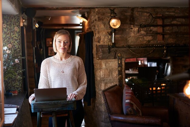 Portret van vrouwelijke receptioniste die op laptop werkt bij het inchecken van het hotel