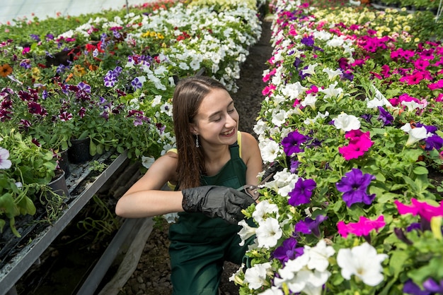 Portret van vrouwelijke tuinman die schort draagt tijdens het werken in kas