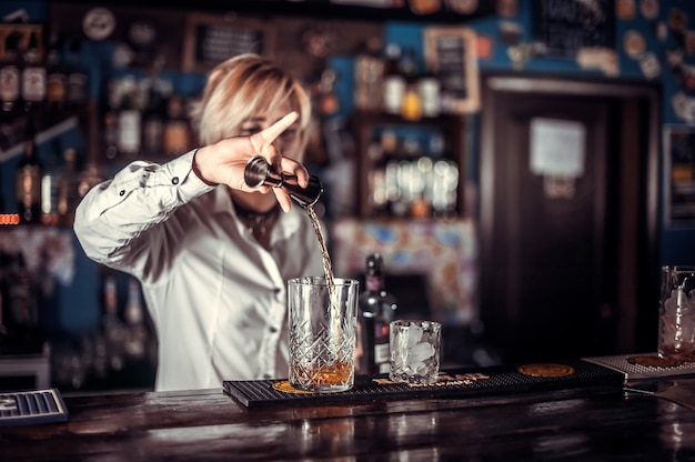 Portret van vrouwenbarman die de laatste hand legt aan een drankje aan de toog