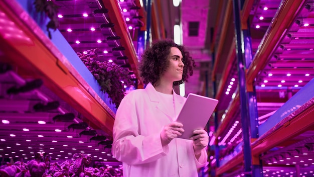 Foto portret van werknemer met tablet op aquaponic boerderij, duurzaam ondernemen en kunstmatige verlichting.