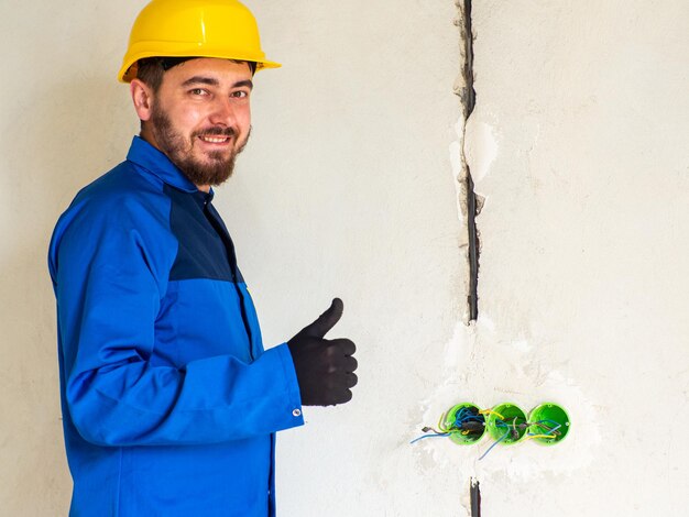 Portret van werknemer of ingenieur in blauwe werkkleding en gele veiligheidshelm