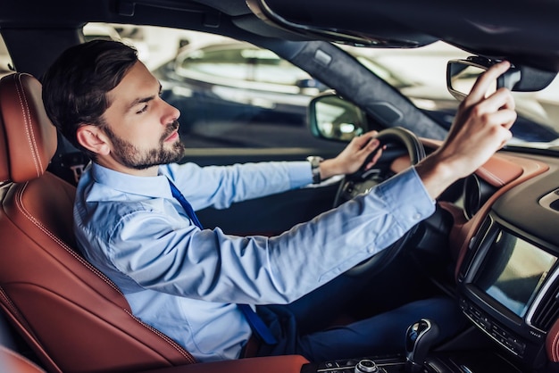 Portret van zakenman die de achteruitkijkspiegel in de auto aanpast