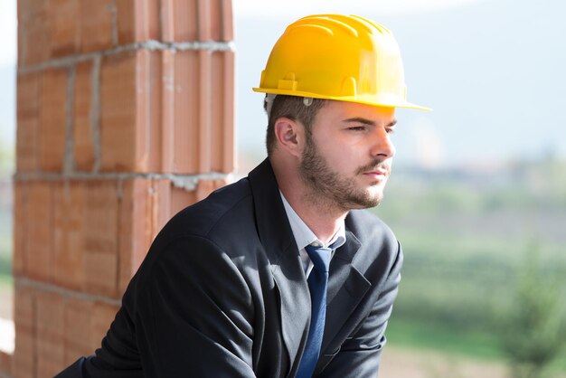 Portret van zakenman met gele helm op bouw