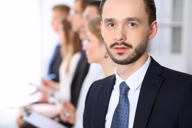 Portret van zakenman tegen een groep mensen uit het bedrijfsleven tijdens een vergadering.