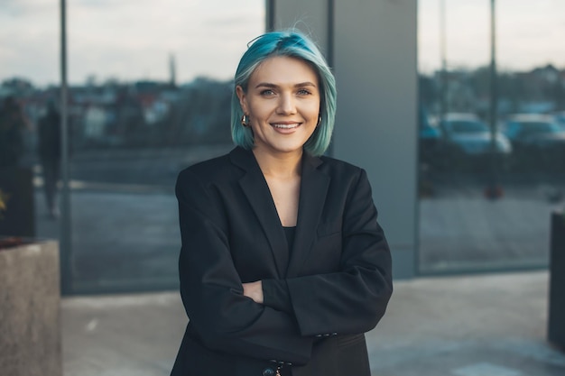 Portret van zakenvrouw met blauw haar buiten poseren met gevouwen armen succesvolle zakenman...