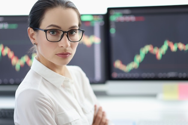 Portret van zakenvrouw met bril op achtergrond van elektronische beursanalyse