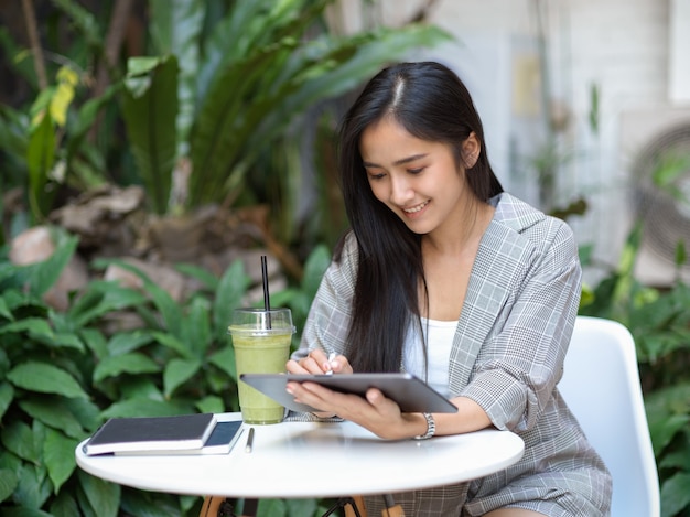 Portret van zakenvrouw werken met digitale tablet op koffietafel in tuin thuis