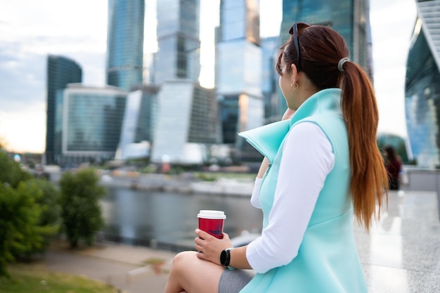 Portret van zakenvrouw zitten met telefoon en kopje koffie buiten